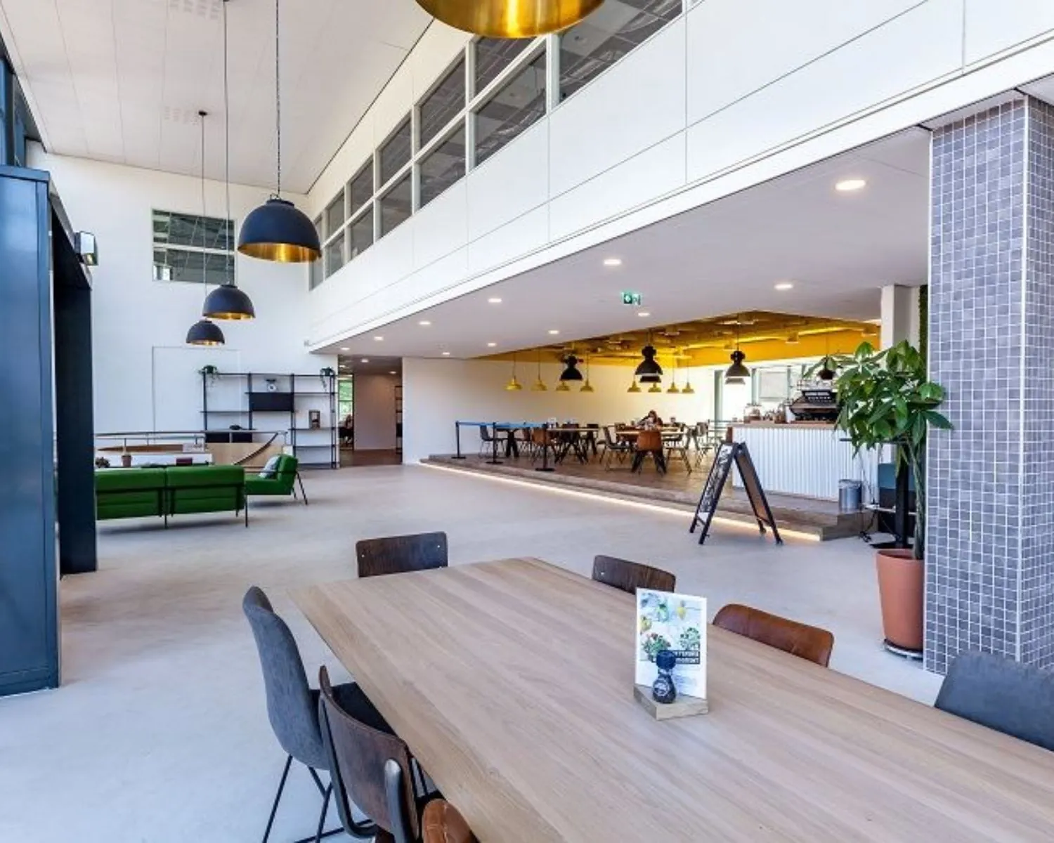 Moderne, open kantoorruimte aan de Polarisavenue met zithoeken, vergadertafels en een koffiebar.