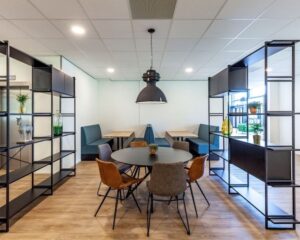 Moderne kantoorruimte met ronde vergadertafel, zitnissen en open stalen wandrekken op Polarisavenue 130-148.