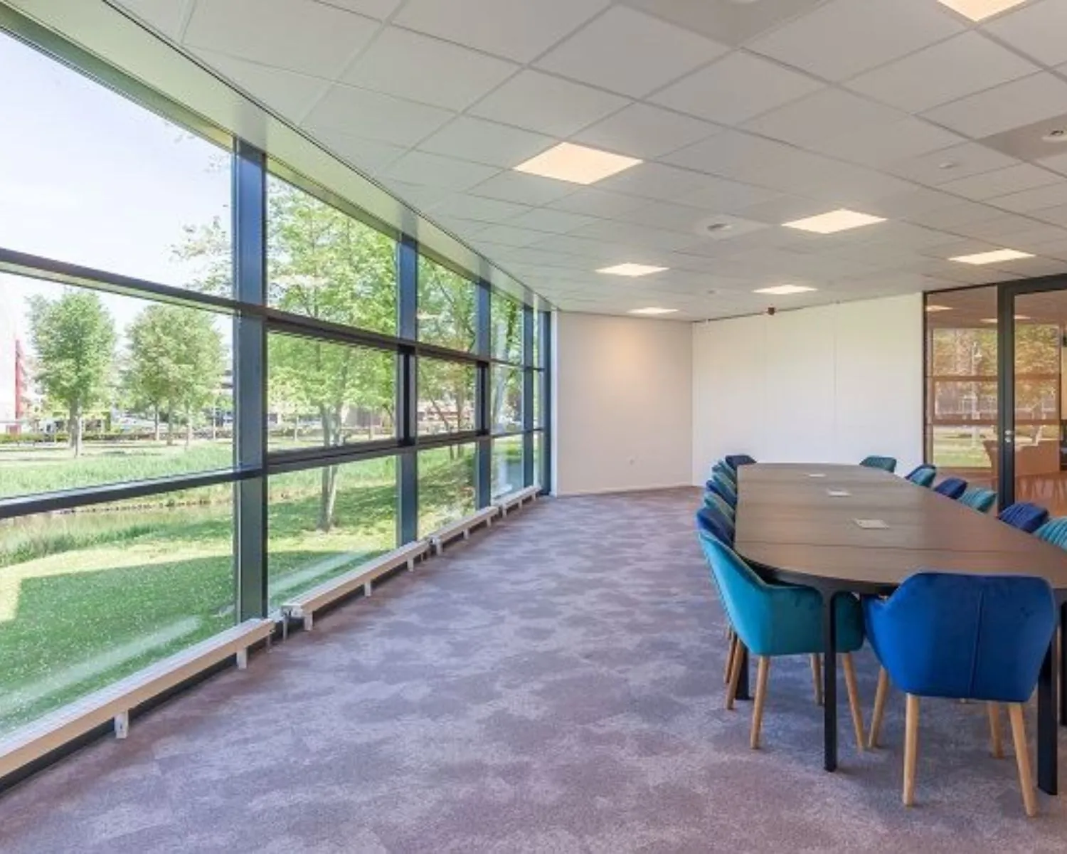 Moderne vergaderruimte met grote ramen en een lange tafel in een kantoorpand aan de Polarisavenue.