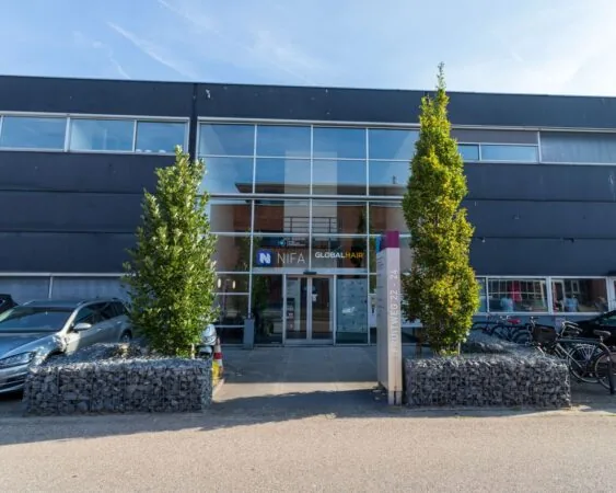 Voorgevel van een modern kantoorpand aan de Pompoenweg met glazen entree en bedrijfsnaam NIFA Global Hair.