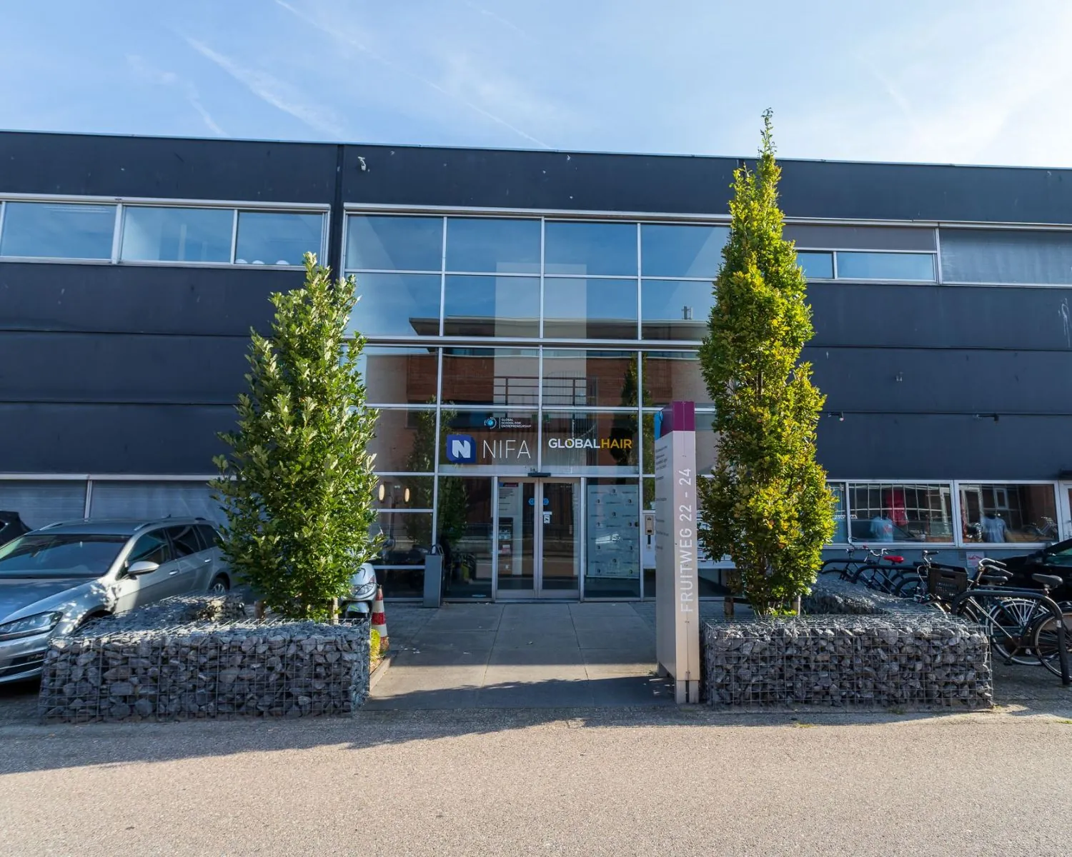 Voorgevel van een modern kantoorpand aan de Pompoenweg met glazen entree en bedrijfsnaam NIFA Global Hair.