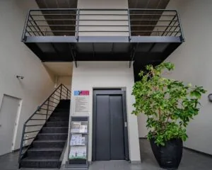 Entreehal van kantoorpand aan de Pompoenweg met trap, lift en grote plant in een zwarte pot.
