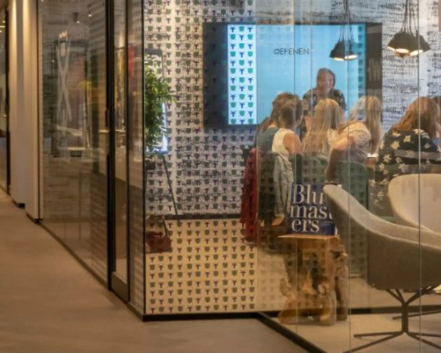 Vergaderruimte met glazen wanden in een modern kantoorpand aan het Prins Bernhardplein 200 in Amsterdam, waar een groep mensen een presentatie bijwoont.