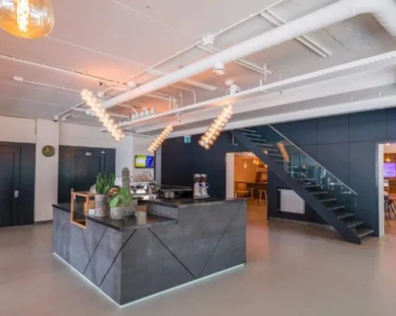 Moderne kantoorruimte met een koffiebalie, industriële verlichting en een glazen trap aan de Roggestraat 111 in Apeldoorn.