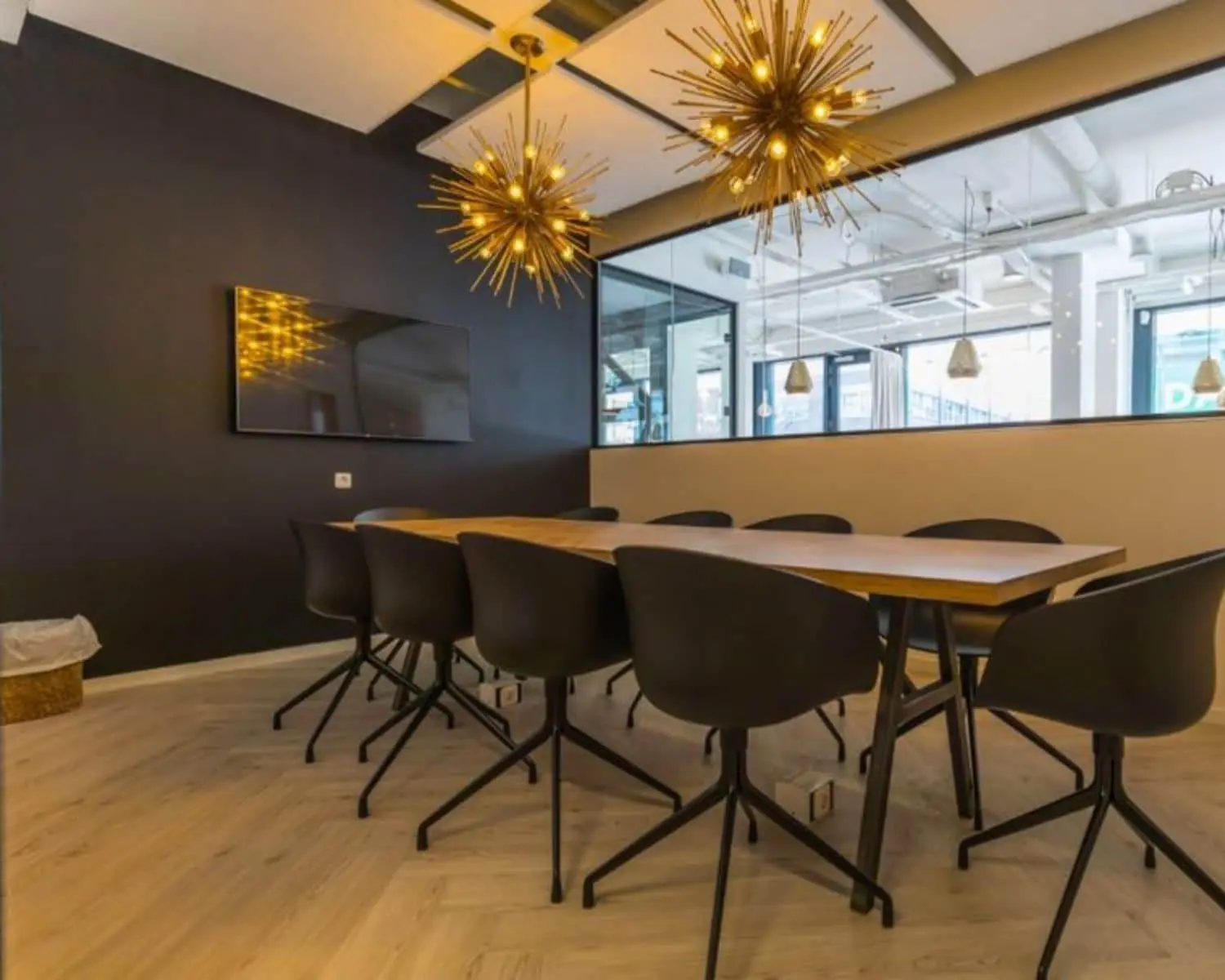 Moderne vergaderruimte met lange houten tafel, zwarte stoelen en opvallende hanglampen in kantoor aan de Roggestraat 111 in Apeldoorn.