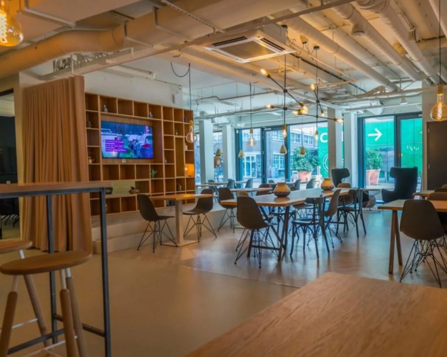 Moderne, open kantooruimte aan de Roggestraat 111 in Apeldoorn met veel daglicht, werkplekken en een zitgedeelte met televisie.