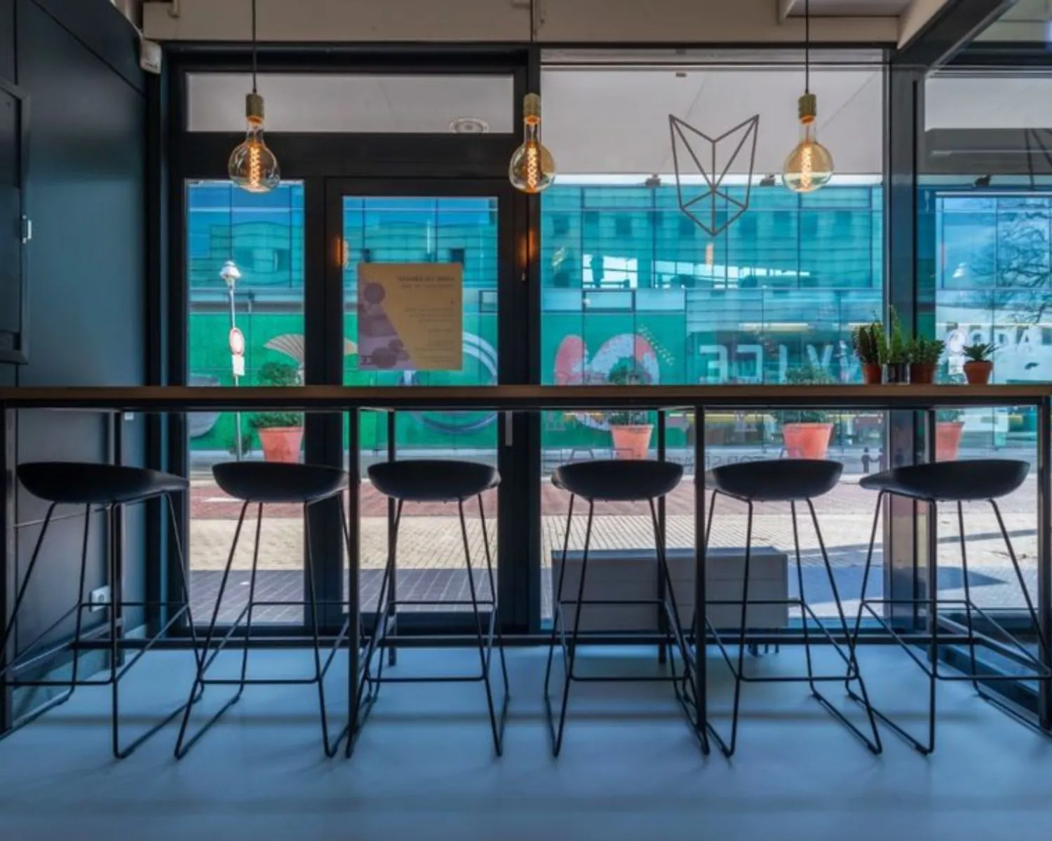 Moderne kantoorlounge bij Roggestraat 111 in Apeldoorn met hoge zitplaatsen, hanglampen en uitzicht op de straat.