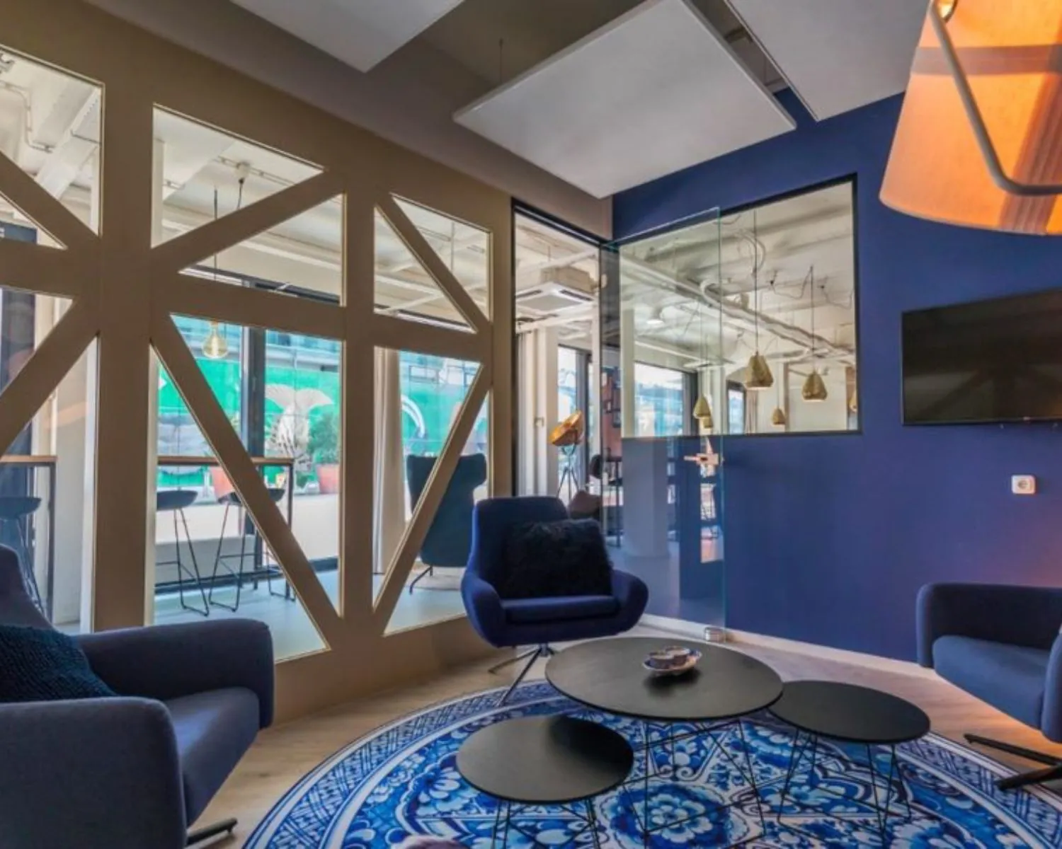 Moderne loungeruimte in kantoor aan de Roggestraat 111 in Apeldoorn met blauwe muren, glazen wanden en stijlvolle meubels.