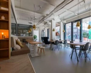 Moderne kantoorruimte met grote ramen, houten tafels en een lichte, open inrichting aan de Roggestraat 111 in Apeldoorn.