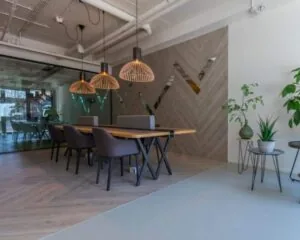 Moderne kantoorruimte in Apeldoorn met houten vergadertafel, designverlichting en glazen wand.