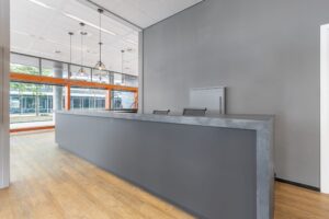 Moderne ontvangstruimte met grijze balie, houten vloer en grote ramen in een kantoorpand aan het Smallepad 32 in Amersfoort.
