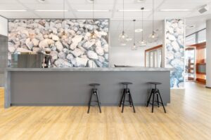 Moderne kantoorruimte met een grijze bar, barkrukken en een opvallende muur met steenmotief aan het Smallepad 32 in Amersfoort.