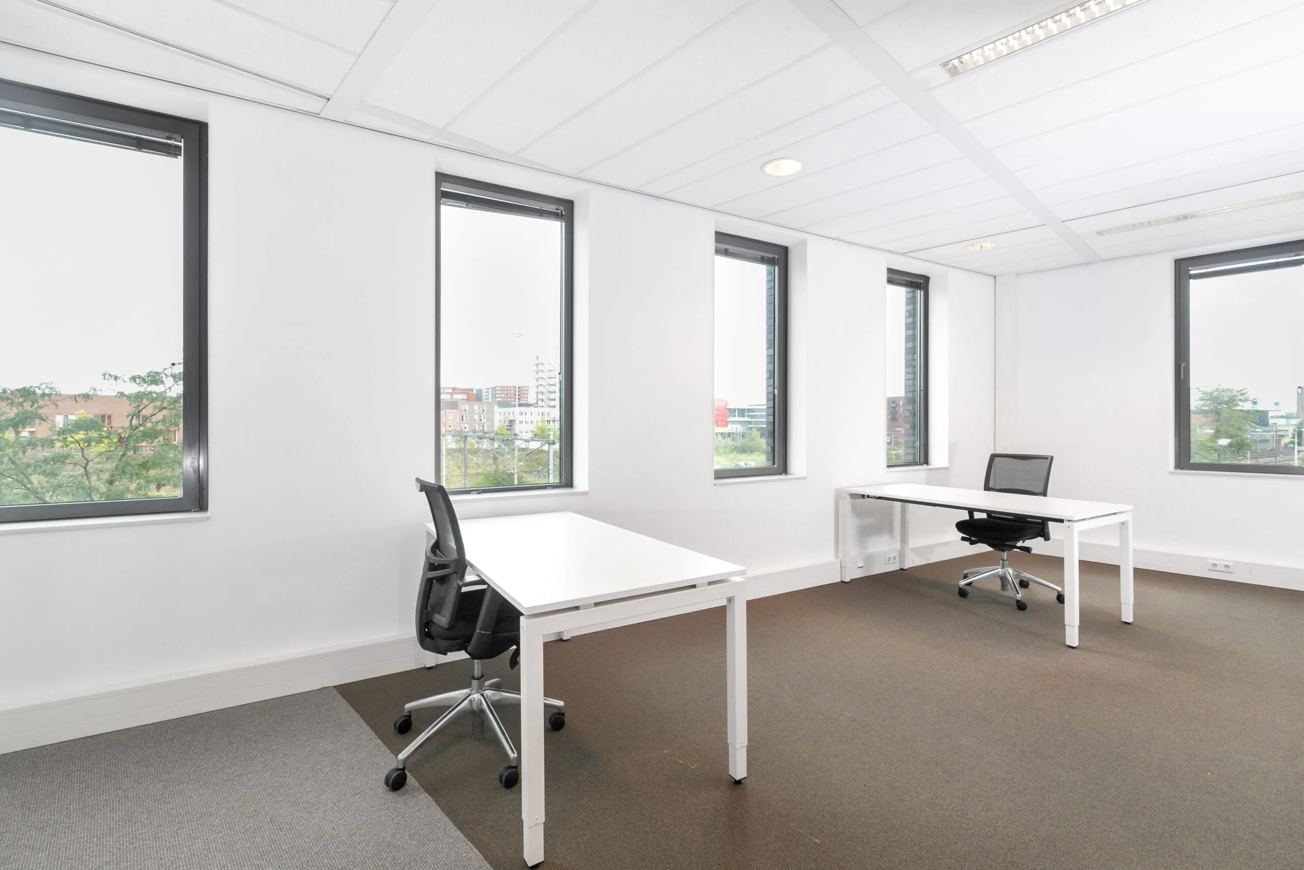 Lichte en moderne kantoorruimte met twee bureaus en grote ramen aan het Smallepad 32 in Amersfoort.
