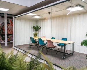 Moderne vergaderruimte met glazen wanden en kleurrijke stoelen aan de Tarasconweg 2 in Eindhoven.