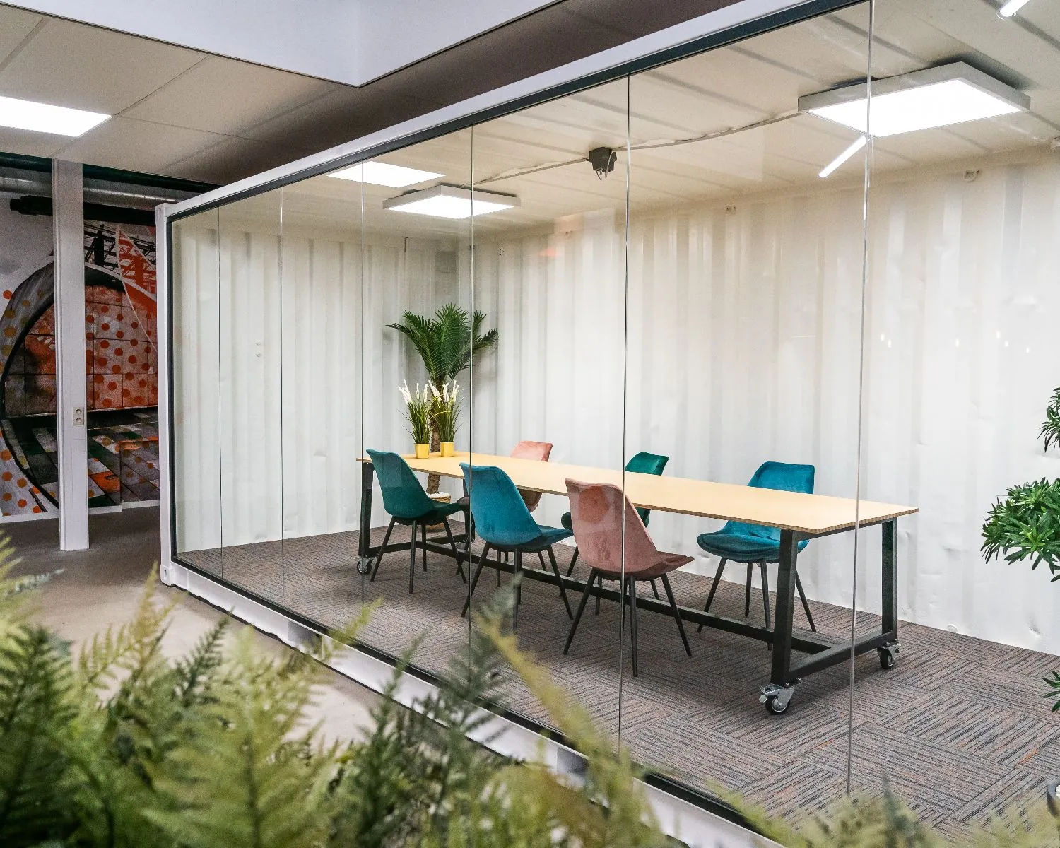 Moderne vergaderruimte met glazen wanden en kleurrijke stoelen aan de Tarasconweg 2 in Eindhoven.