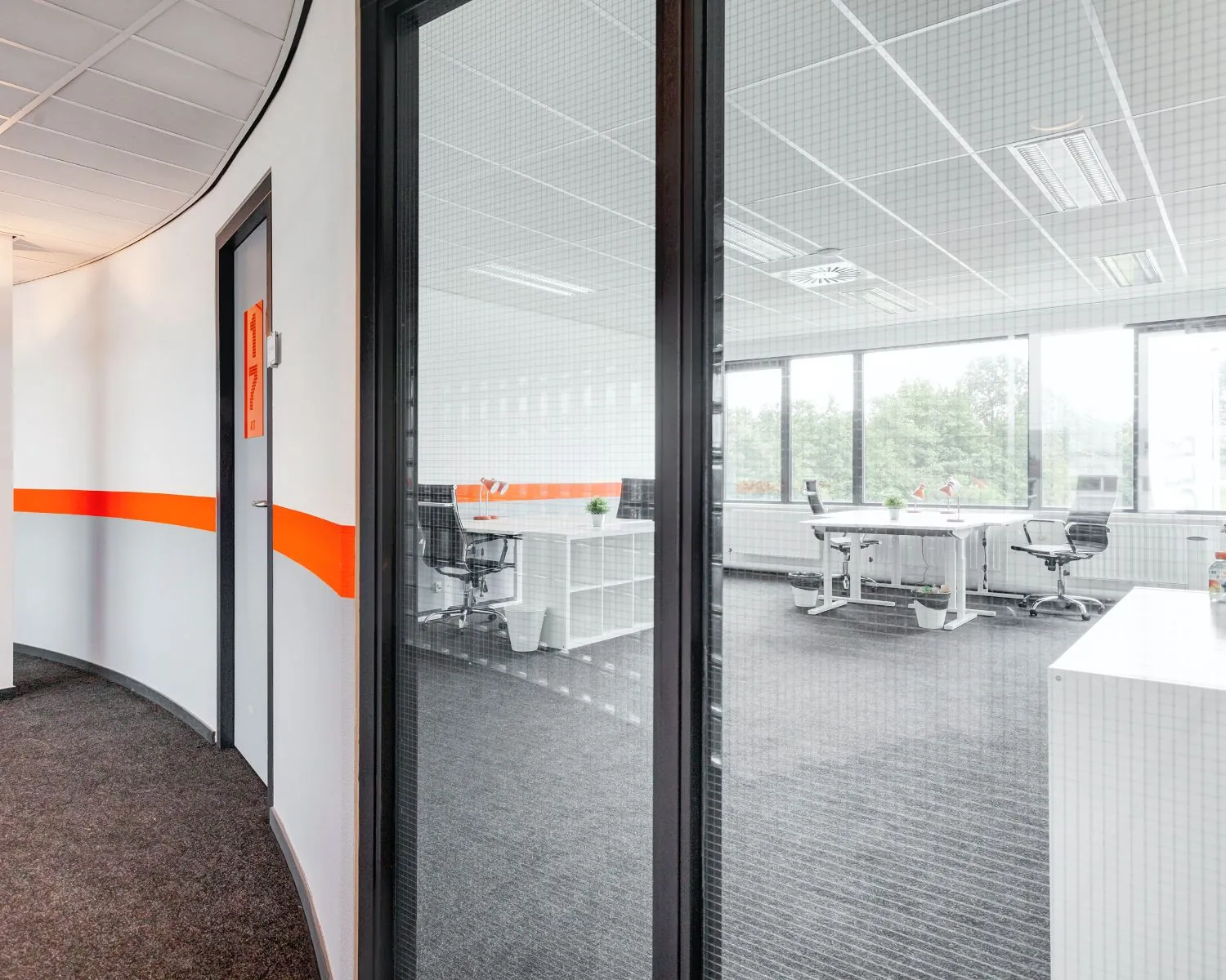 Moderne kantoorruimte aan de Tarasconweg 2 in Eindhoven met glazen binnenwand en meerdere bureaus met stoelen.