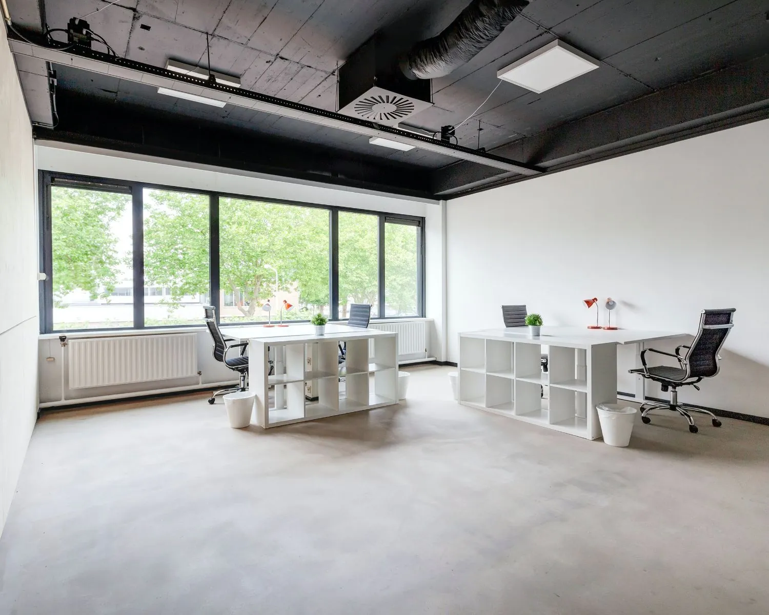 Moderne kantoorruimte met grote ramen, twee bureaus en ergonomische stoelen aan de Tarasconweg 2 in Eindhoven.