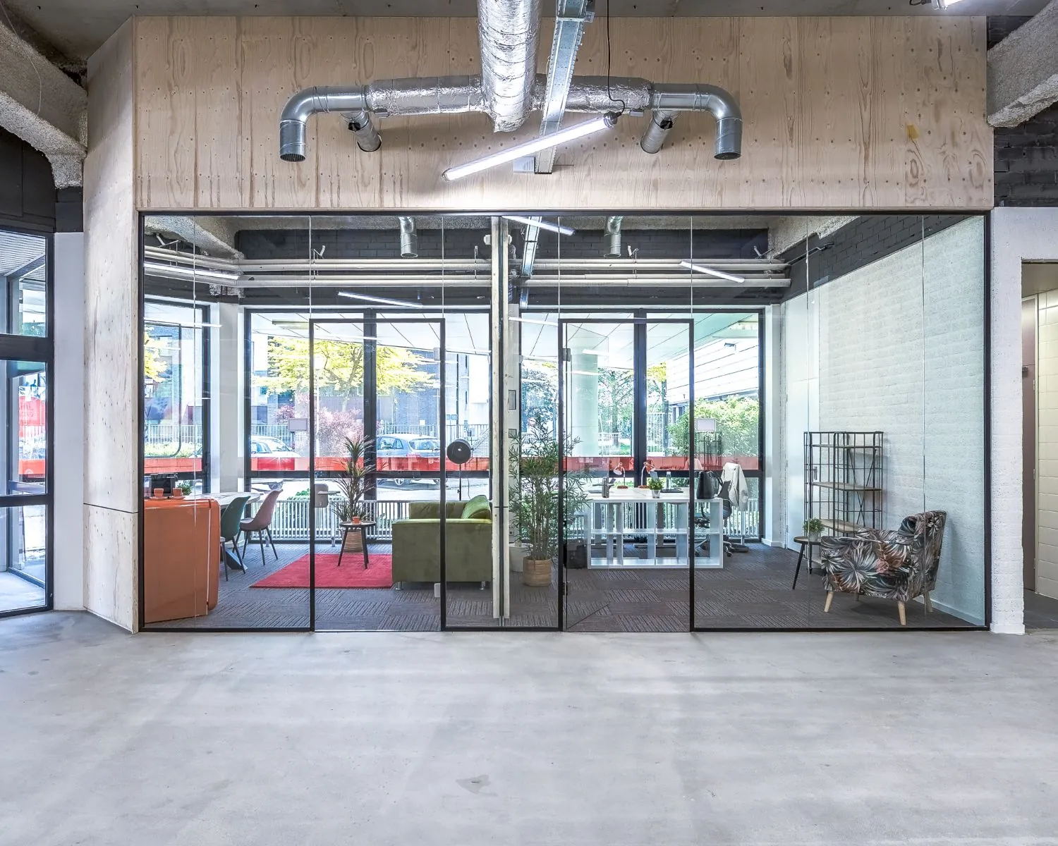 Moderne kantoorruimte met glazen wanden aan de Tarasconweg 2 in Eindhoven, ingericht met zitjes, planten en werkplekken.