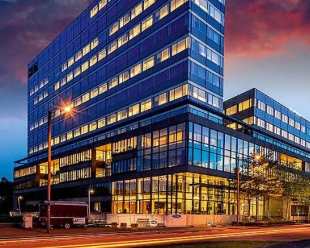 Modern kantoorgebouw aan de Thomas R. Malthuslaan 1 in Amsterdam, verlicht tijdens de avondschemering.