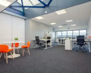 Moderne en lichte kantoorruimte met werkplekken, vergadertafel en oranje stoelen aan de Transistorstraat 151 in Almere.