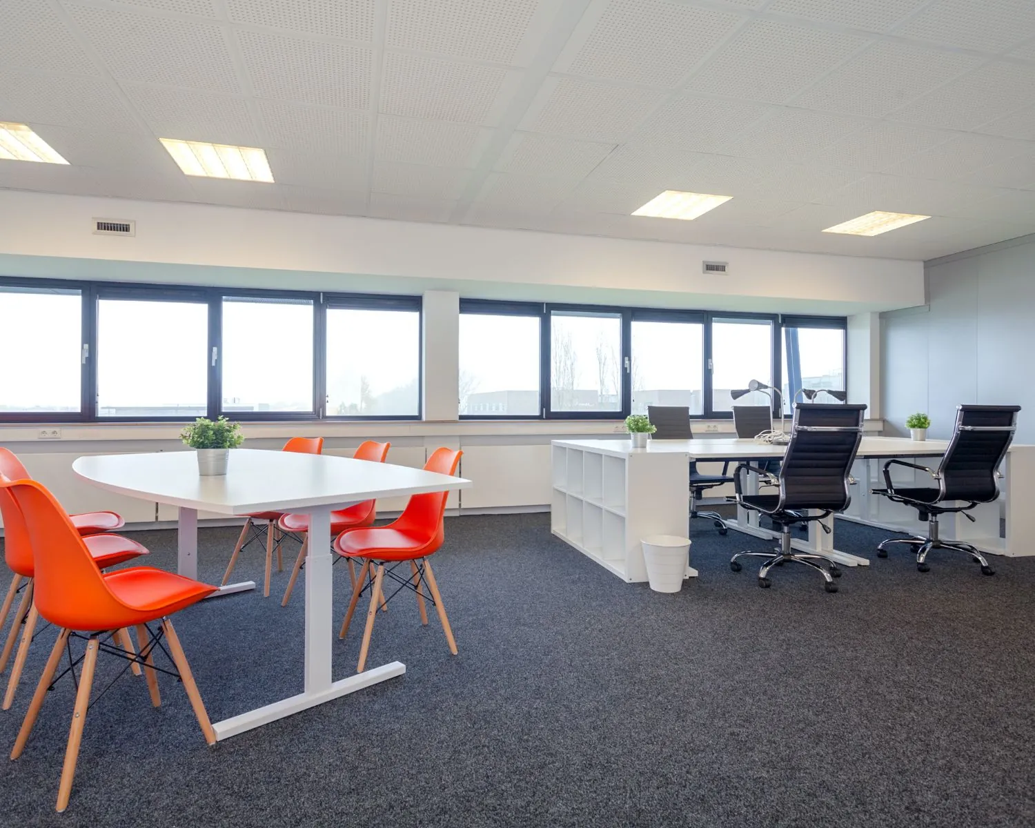 Moderne kantoorruimte met witte bureaus, oranje stoelen en grote ramen aan de Transistorstraat 151 in Almere.