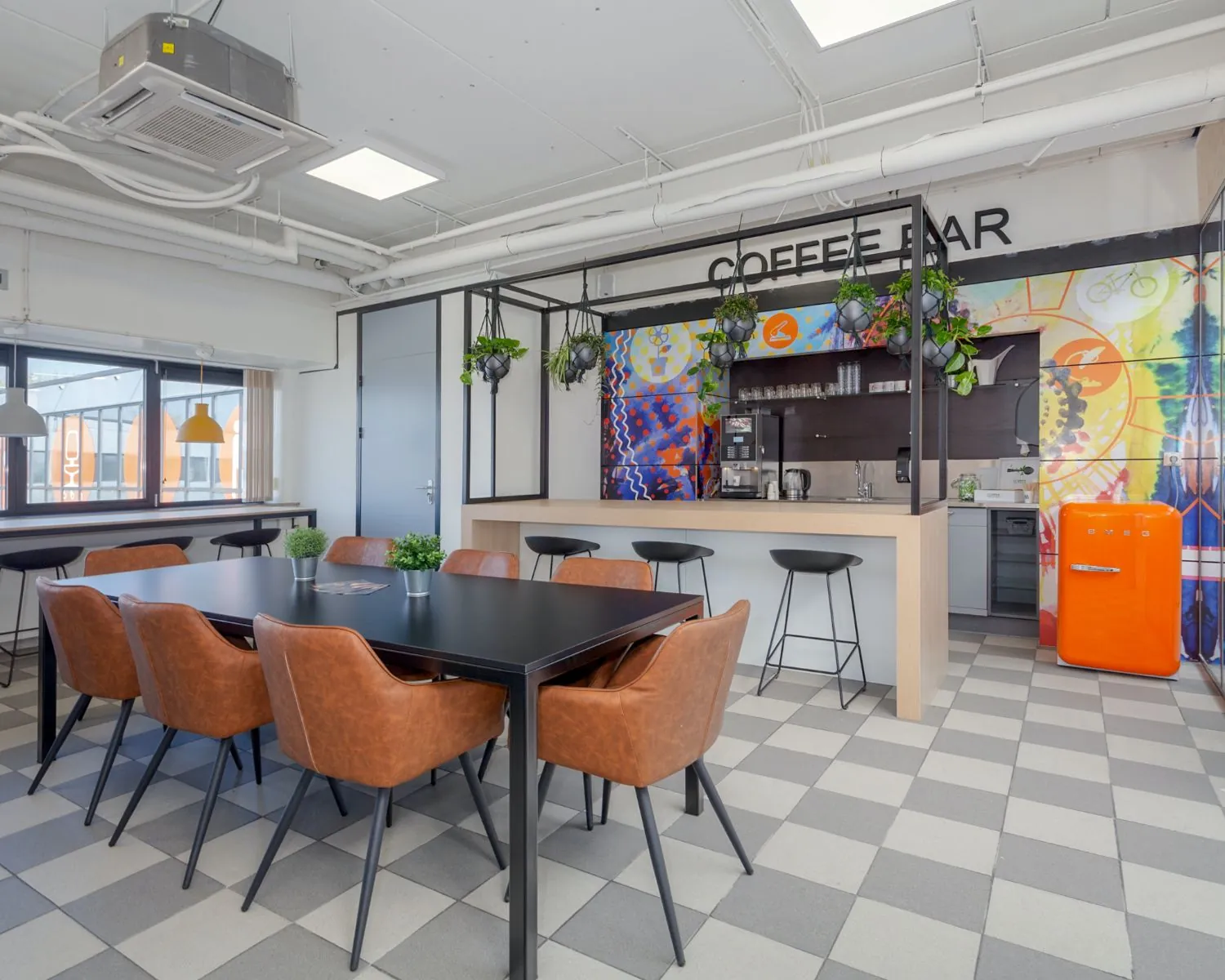 Moderne kantoorruimte in Almere met een kleurrijke koffiebar, vergadertafel en industriële inrichting.