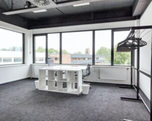 Moderne, lichte kantoorruimte met een bureau, bureaustoelen en kapstok aan de Turfstekerstraat 63 in Aalsmeer.