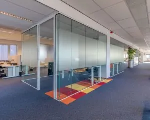 Moderne kantoorruimte met glazen vergaderruimtes en kleurrijke vloeraccenten aan de Vossenstraat 6.