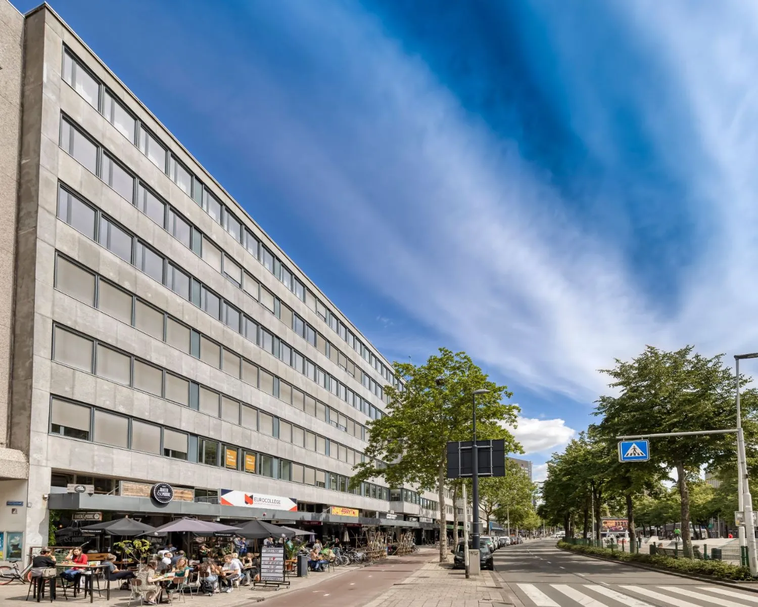 Straatbeeld met een kantoorgebouw aan de Westblaak 107-147 met horeca en winkels op de begane grond.