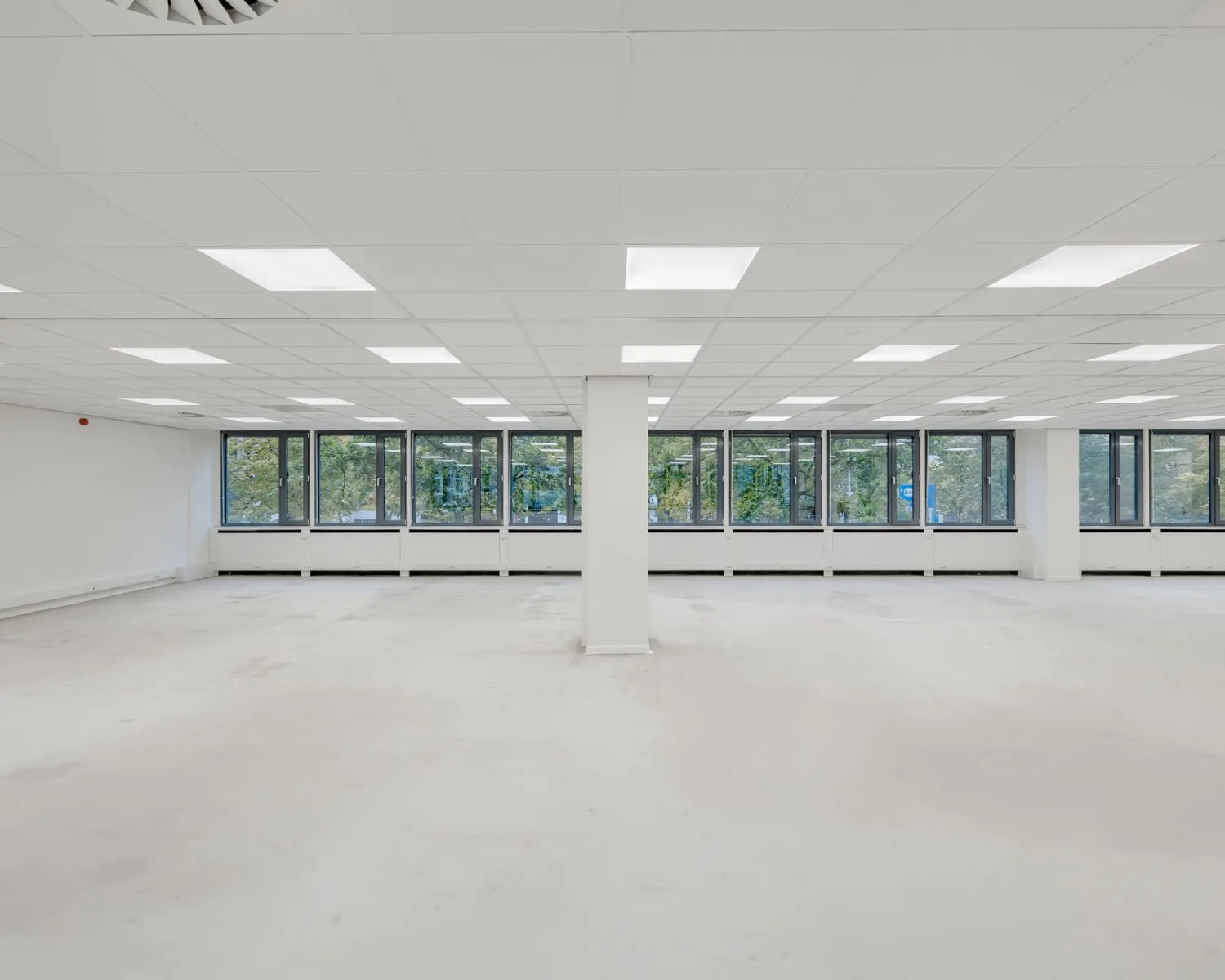 Lichte, lege kantoorruimte met systeemplafond en grote ramen aan de Westblaak 107-147.