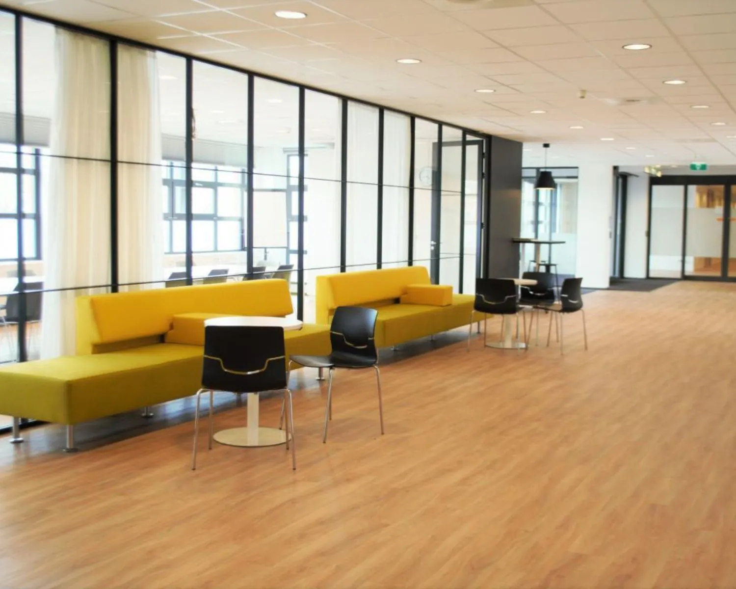 Moderne kantoorruimte aan de Zonnebaan 8 in Utrecht met gele zitbanken, zwarte stoelen en glazen wanden.