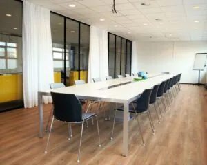 Moderne vergaderruimte met lange tafel, veel stoelen en glazen wanden in een kantoor aan de Zonnebaan 8 in Utrecht.