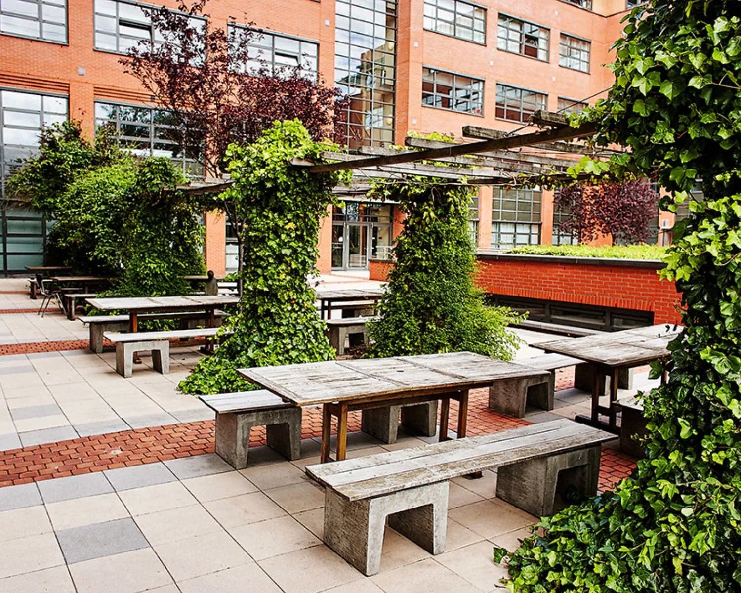 Buitenruimte met picknicktafels en groene pergola bij kantoorgebouw aan de Zonnebaan 8 in Utrecht.
