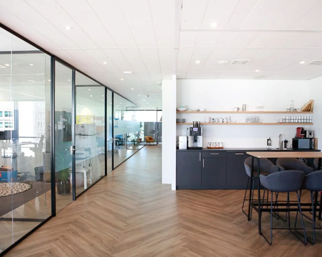 Moderne kantoorruimte in Amsterdam met een glazen vergaderruimte en een open keuken met zitgedeelte.