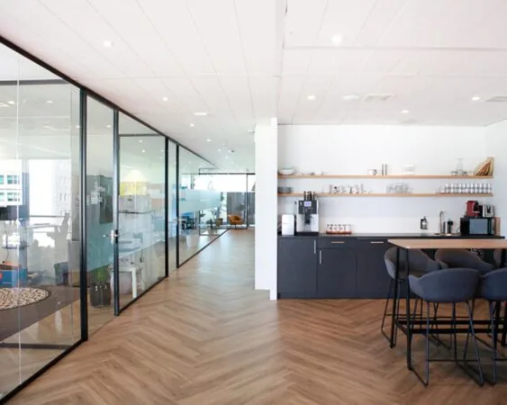 Moderne kantoorruimte in Amsterdam met een glazen vergaderruimte en een open keuken met zitgedeelte.