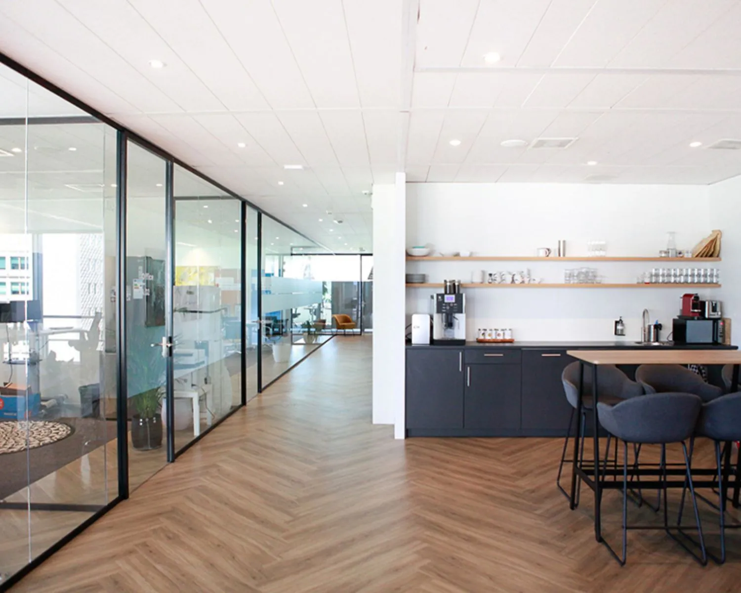 Moderne kantoorruimte in Amsterdam met een glazen vergaderruimte en een open keuken met zitgedeelte.