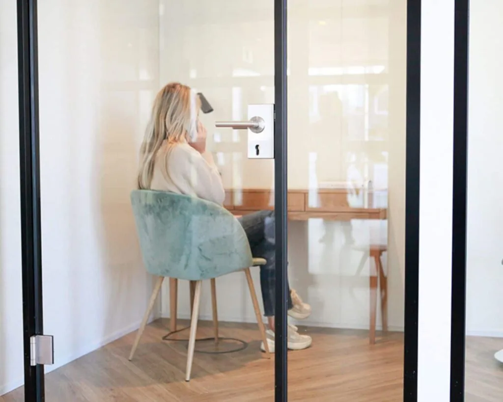 Vrouw werkt of telefoneert in een afgesloten kantoorruimte met glazen deur in Amsterdam.