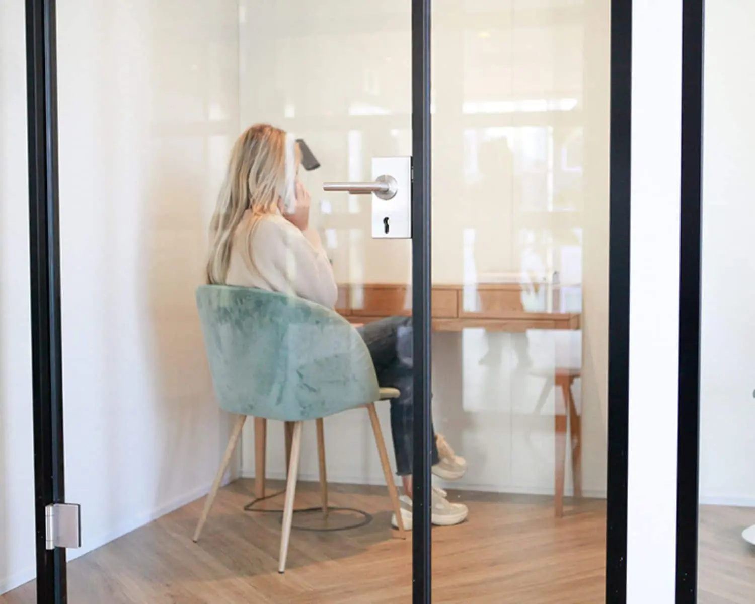 Vrouw werkt of telefoneert in een afgesloten kantoorruimte met glazen deur in Amsterdam.