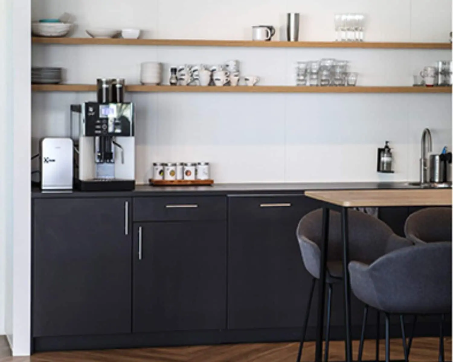 Moderne kantoorkeuken met koffieautomaat, open planken en een zitgedeelte in een kantoorruimte aan de entree 230-260 in Amsterdam.