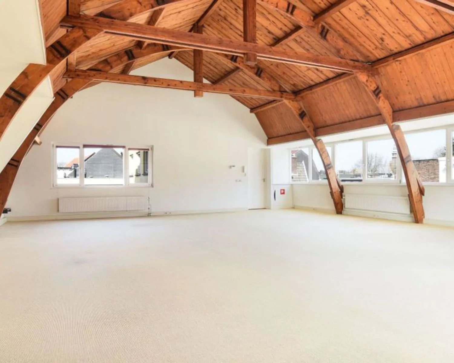 Lichte kantoorruimte met houten balkenplafond en grote ramen aan het Houtplein 22 in Haarlem.