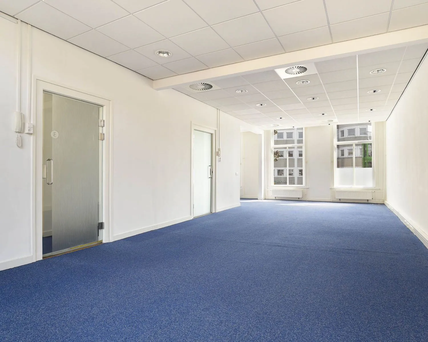 Lichte kantoorruimte met blauwe vloerbedekking aan het Houtplein 22 in Haarlem.