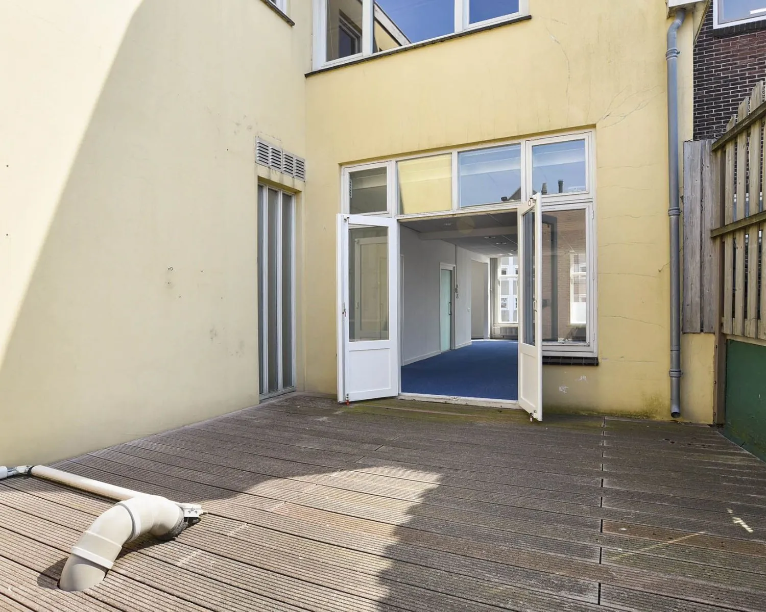 Houten terras met openstaande deuren naar een kantoorruimte aan het Houtplein 22 in Haarlem.