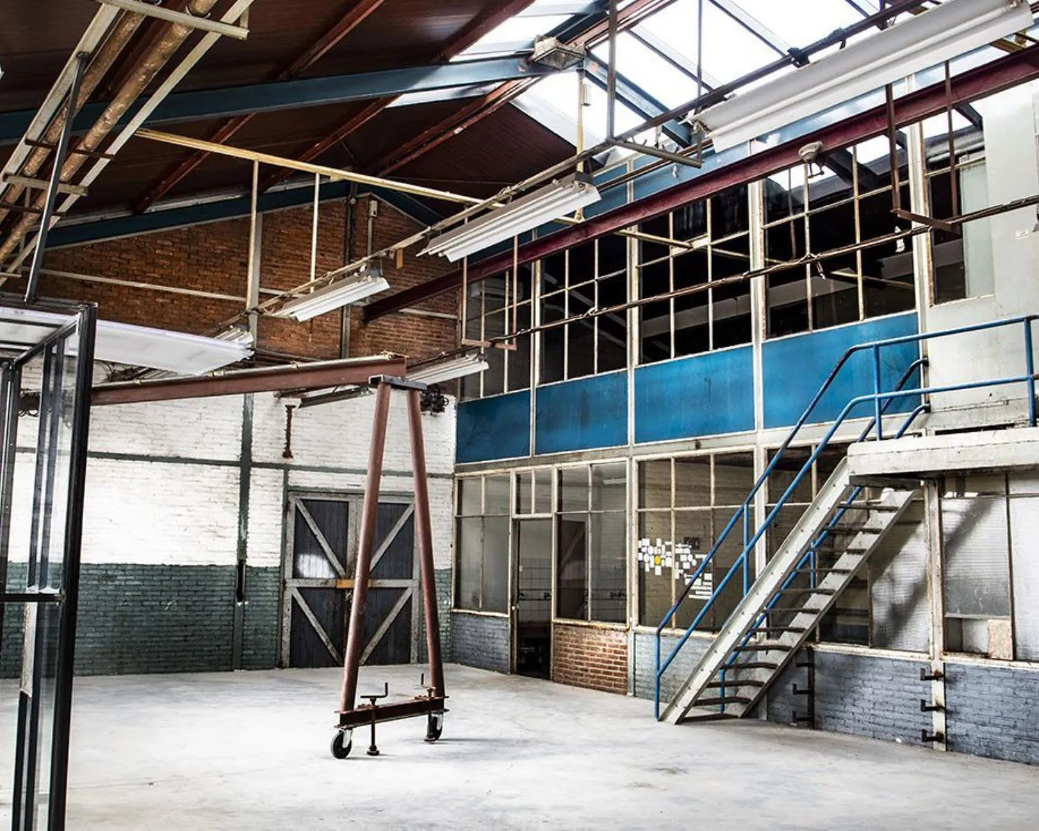 Ruime industriële kantoorruimte te huur aan Kalkhovenplein 3b in Halfweg, met hoge plafonds, metalen trap en grote ramen.