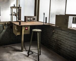 Industriële werkhoek met oud metalen bureau, kruk en vintage apparatuur in een kantoorruimte aan het Kalkhovenplein 3b in Halfweg.