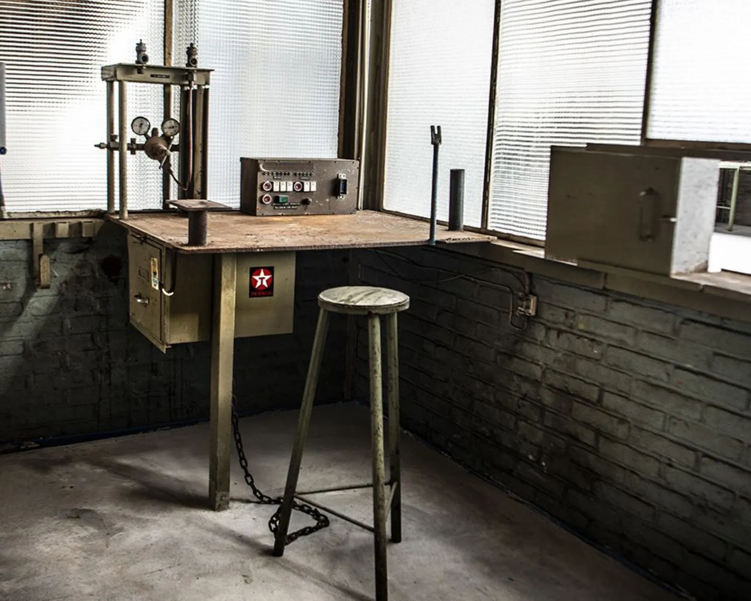 Industriële werkhoek met oud metalen bureau, kruk en vintage apparatuur in een kantoorruimte aan het Kalkhovenplein 3b in Halfweg.