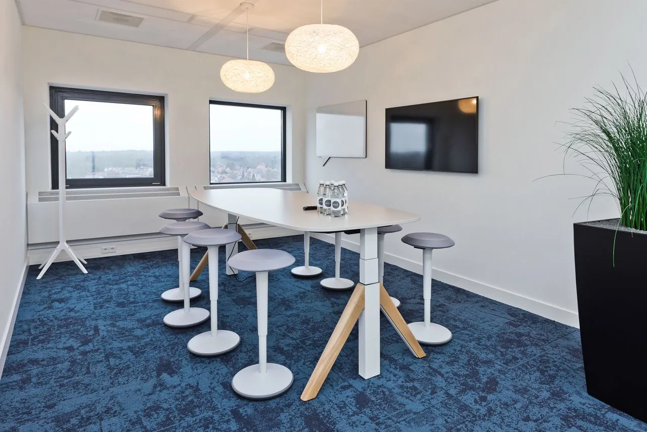 Moderne vergaderruimte in kantoorpand Kennemerhaghe in Heemstede met hoge tafel, krukken, presentatieschermen en uitzicht op de stad.