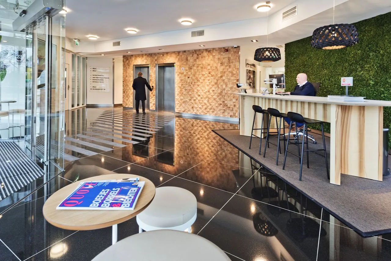 Moderne ontvangsthal van kantoorgebouw Kennemerhaghe in Heemstede met receptiebalie, zitgedeelte en liften.