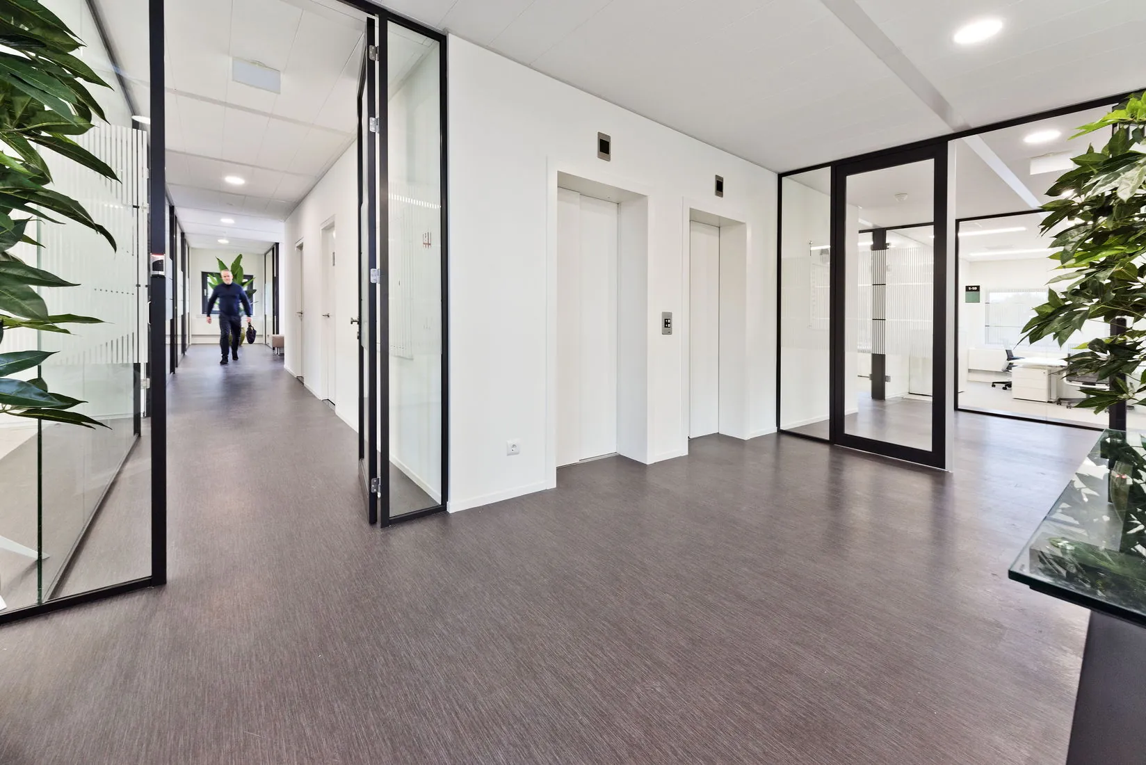 Moderne en lichte kantoorruimte met glazen wanden, twee liften en een gang in het gebouw Kennemerhaghe aan de Leidsevaartweg 99 in Heemstede.