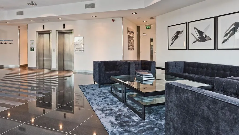 Moderne wachtruimte in kantoorgebouw Kennemerhaghe met luxe zithoeken, glazen salontafels en twee liften.