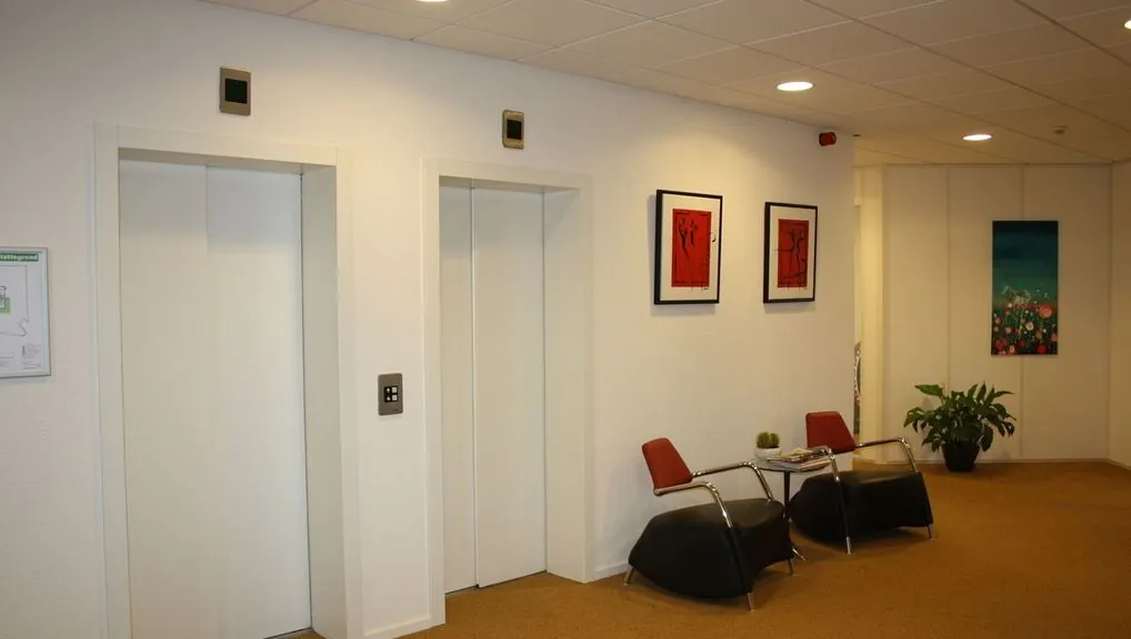 Wachtruimte met twee liften, zitplaatsen en moderne kunst in kantoorgebouw Kennemerhaghe in Heemstede.